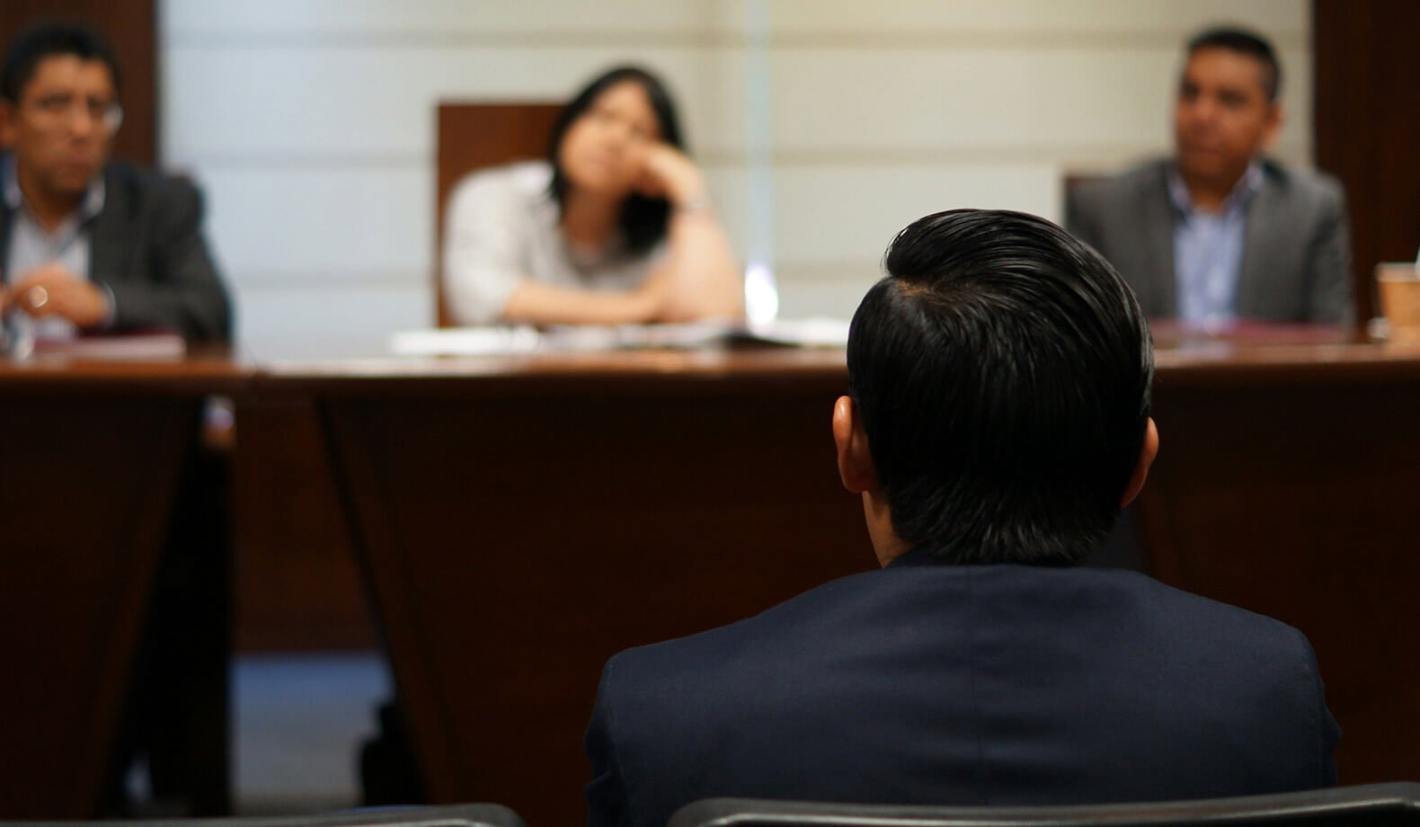A male witness in front of a panel of three people. Photo by Saul Bucio on Unsplash